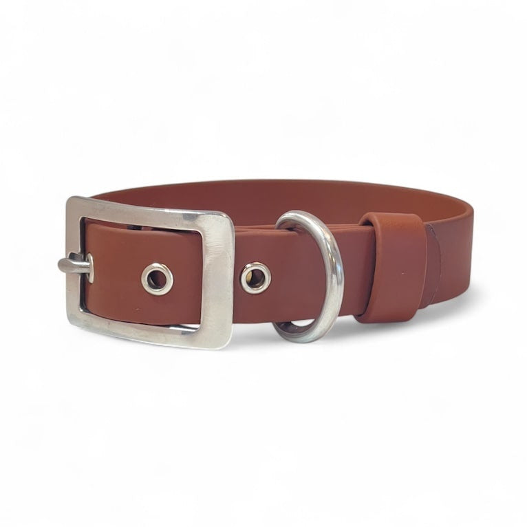 Brown BioThane dog collar with a sturdy metal buckle and D-ring, featuring reinforced metal eyelets for added durability. The collar is designed for both strength and comfort, showcased against a plain white background.